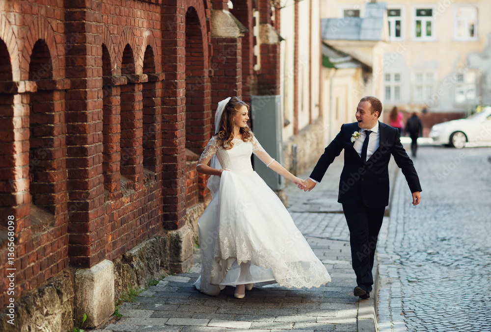 Happy beautiful newlyweds walking on the street