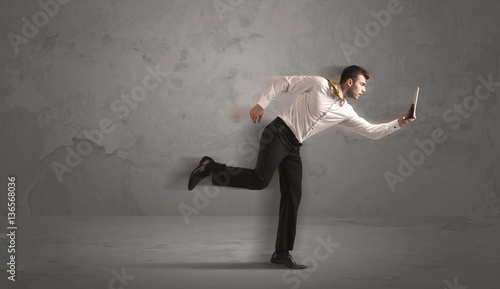 Running businessman with device in hand