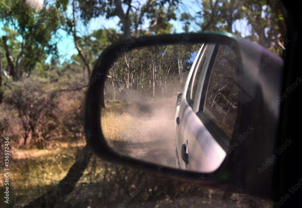 Reflections in a side view mirror of a car driving in the bush. Rear view car mirror in forest live green. Dirt road leading up to a slavery plantation. Concept of 4wd off-road driving in the nature. Reflections in a side view mirror of a car driving in the bush. Rear view car mirror in forest live green. Dirt road leading up to a slavery plantation. Concept of 4wd off-road driving in the nature.