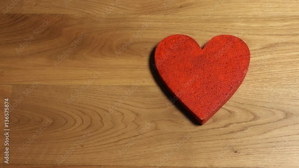 Beautiful female hands putting red heart shape on wooden table. Love, Valentine's day, care concepts, free space for inscriptions. 4K video