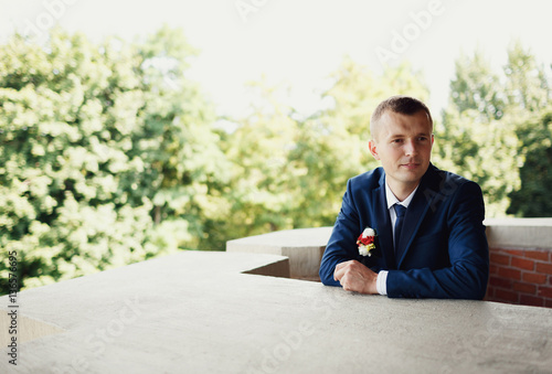 Groom is sitting on the hotel's balcony