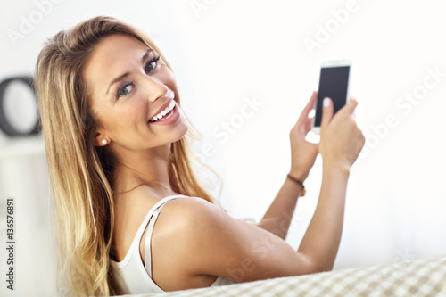 Happy woman with smartphone on sofa