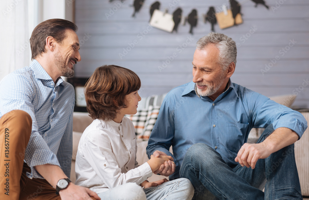 Cheerful positive man shaking his grandsons hand Cheerful positive man shaking his grandsons hand