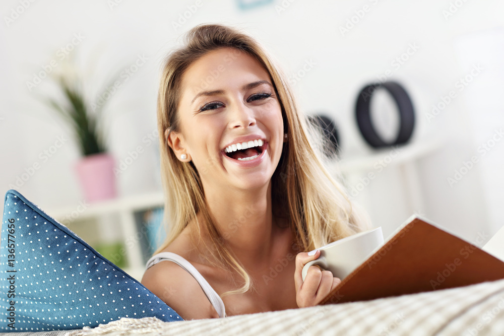 Naklejka premium Happy woman reading on sofa