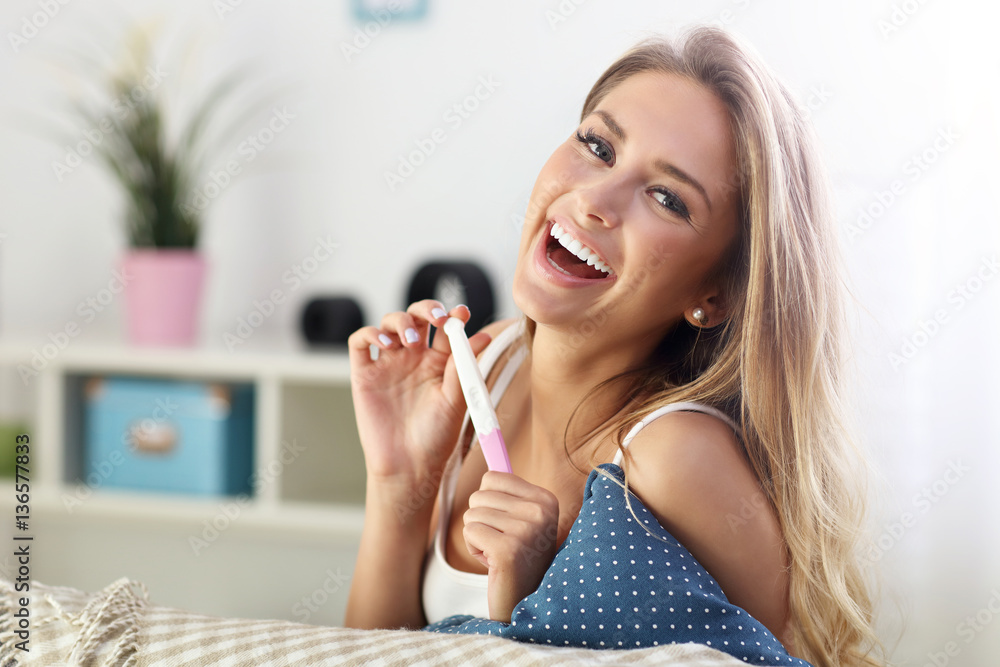 Fototapeta premium Happy woman with pregnancy test at home