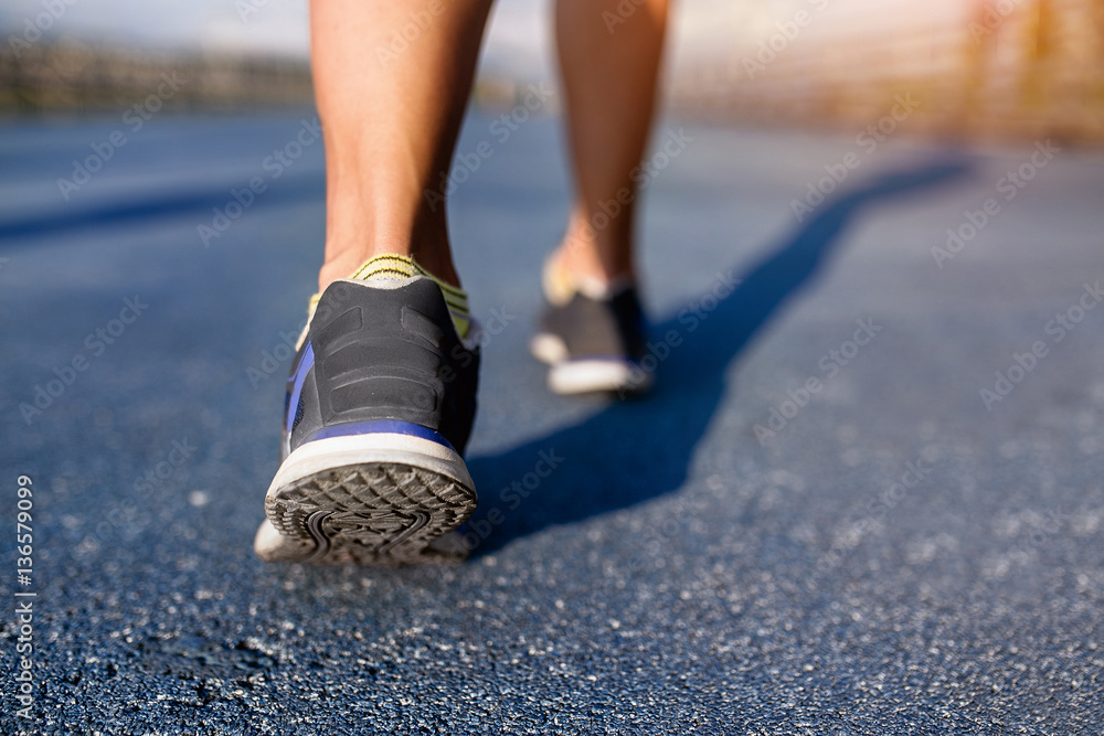 Woman muscle runner feet on road closeup on shoe