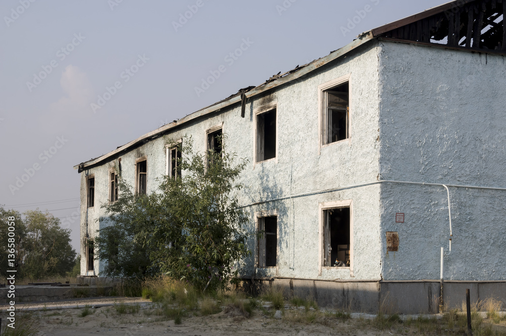 Burnеd light blue two-storeyed building with green trees. After fire Burnеd light blue two-storeyed building with green trees. After fire