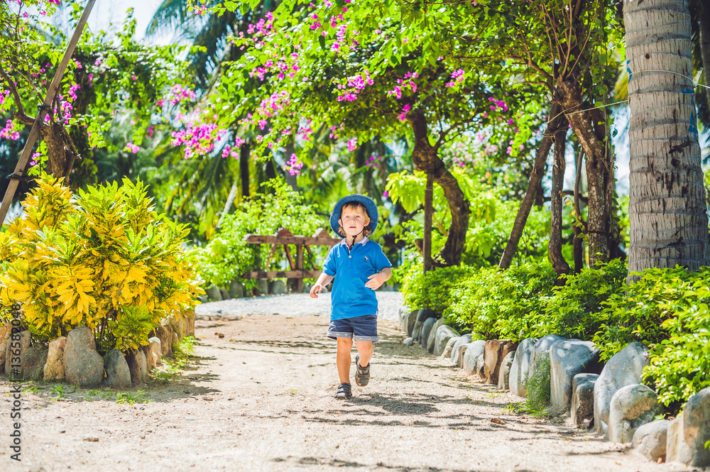 Boy runs through the tropical garden Boy runs through the tropical garden