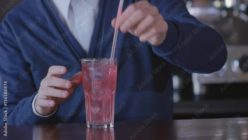 Bartender puts a straw in a glass with a cocktail and transmits it to the client Bartender puts a straw in a glass with a cocktail and transmits it to the client