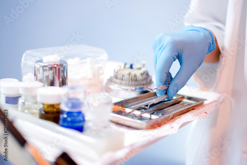 Close up of dentist's hands picking up dental equipment.