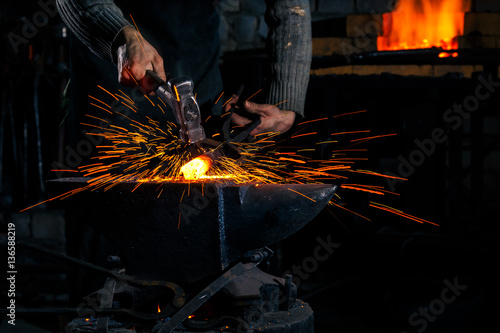 Cuadro en lienzo The blacksmith manually forging the molten metal on the anvil in smithy with spa
