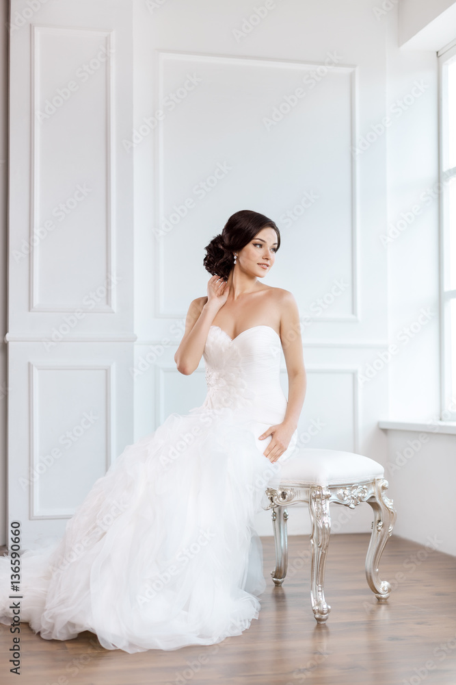 Bride in beautiful dress sitting on chair indoors Bride in beautiful dress sitting on chair indoors