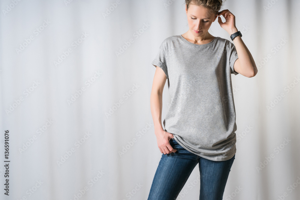 Portrait of pretty young brunette woman in mid 30s wearing casual clothes. Cute  female model in grey t-shirt and classic blue jeans on grey background  Stock Photo - Alamy