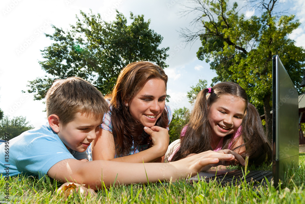 Happy Family using laptop lying on grass Happy Family using laptop lying on grass