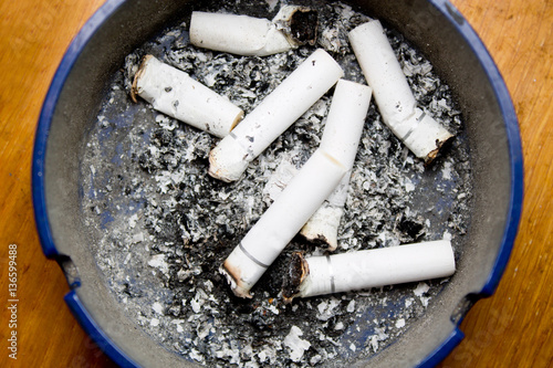 ashtray with cigarette butts on wooden