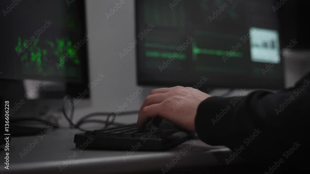 A hacker is preparing for cyber-attack in the underground computer room. A man at a rapid pace enters information. On monitors the information on the preparations for the hacker attack. A hacker is preparing for cyber-attack in the underground computer room. A man at a rapid pace enters information. On monitors the information on the preparations for the hacker attack.