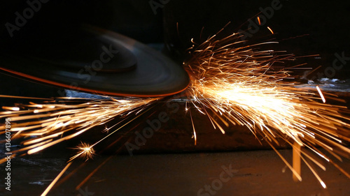 Foto Worker grinding a metal construction with grinding wheel, lots of sparks in fact
