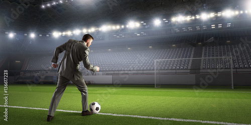 Businessman kicking ball . Mixed media © Sergey Nivens