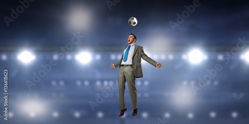 Businessman kicking ball . Mixed media