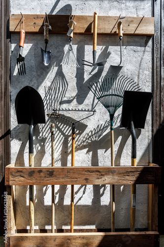 Farm metal garden tools as shovels and rakes hanging on the wall