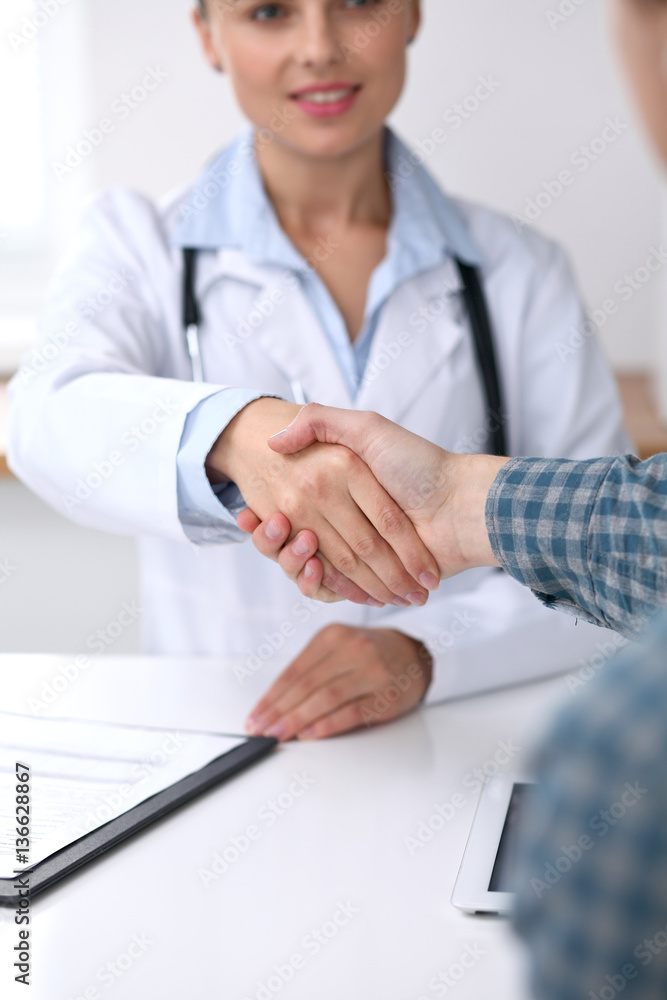 Close up of a doctor woman shaking hands with her male patient. Medicine and trust concept Close up of a doctor woman shaking hands with her male patient. Medicine and trust concept
