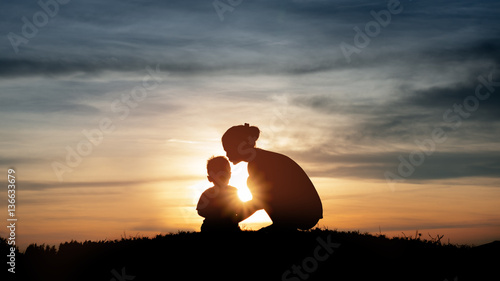 Silhouette of a young mother lovingly kissing her little child o photo