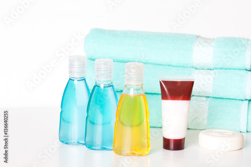 Cosmetics bottles mock ups with shower gel, body moisturizing lotion or shampoo, tube with cream, bar of soap and bath towels background. Spa and beauty saloon motif wallpaper