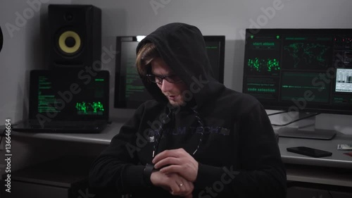 The man with glasses and a hood of cats sitting in a secret location on the head and check the coded messages that come to its smartwatches. In the background is another technique photo