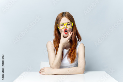 A woman makes gymnastics for her mouth, yellow glasses