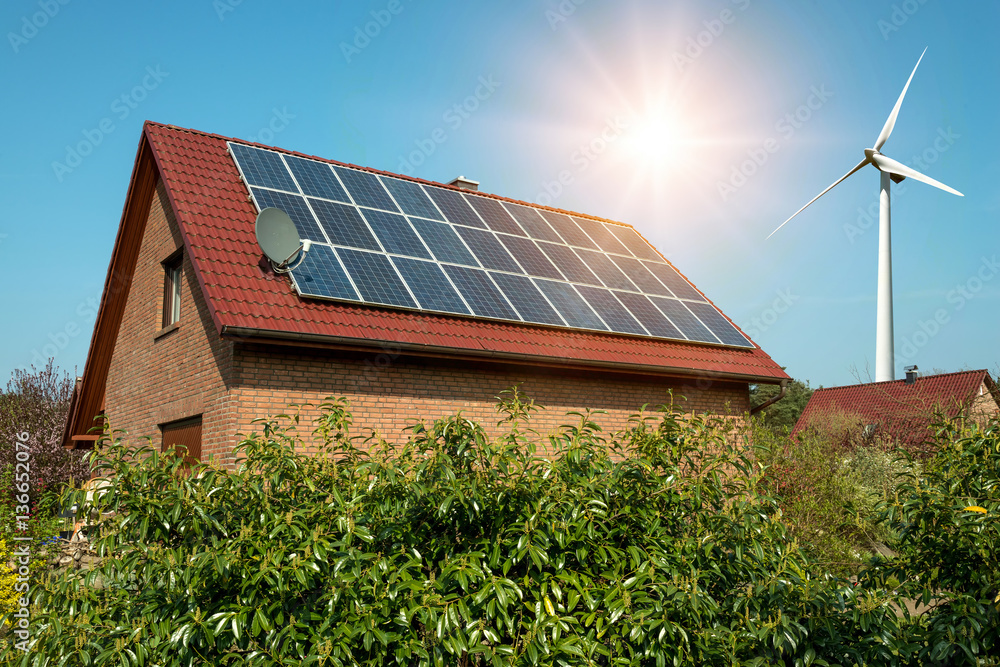 Solar panel on a roof of a house and wind turbins arround - concept of ...