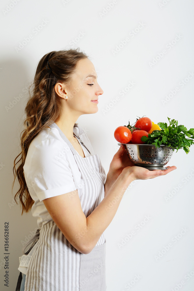 Woman shef holding a colander with vegetables for salad Woman shef holding a colander with vegetables for salad