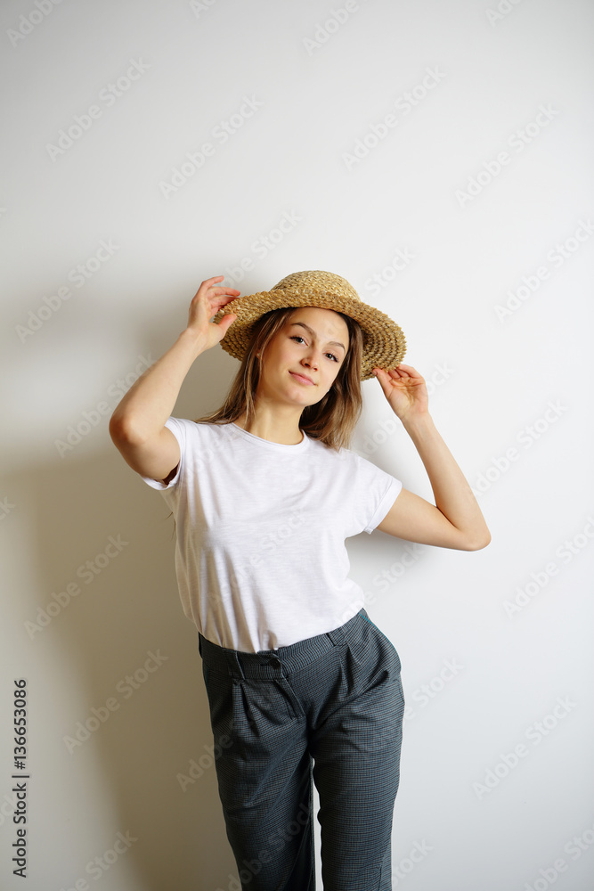 Young woman standing near a white wall, holding hands for a stra Young woman standing near a white wall, holding hands for a stra