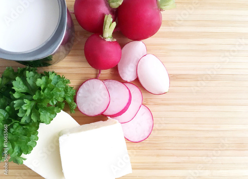 Radishes. Ingredients for radish spread or radish soup - radishes, butter, cream and green parsley. Wooden background. Top view.