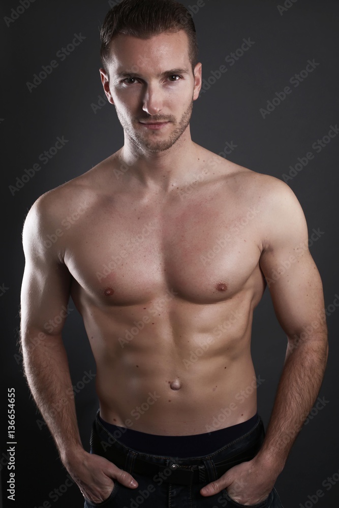 Handsome muscular male posing over a gray background