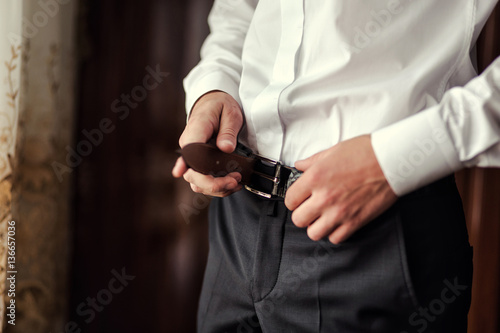 man putting on a belt  Businessman  Politician  man s style  male hands closeup  American businessman  European businessman  a businessman from Asia  People  business  fashion and clothing concept