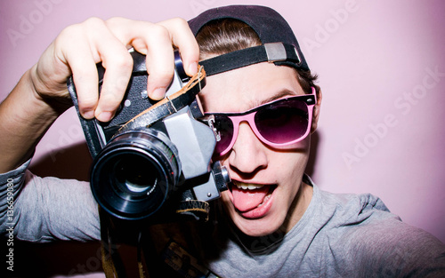 Portrait of the guy with retro camera on the bright background 