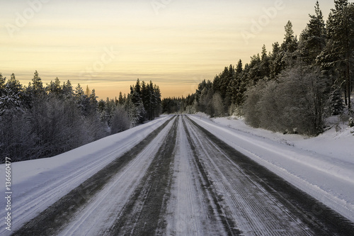 winter road through the forest by car in the evening