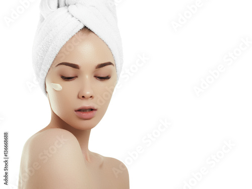 Spa girl. Beautiful young woman after bath touching her face with cosmetic cream. Perfect skin. Skincare. Young skin. Woman beauty face portrait isolated on white background