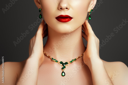 Elegant fashionable woman with jewelry. Beautiful woman with a sapphire necklace. Beauty young model with a diamond pendant on a gray background. Jewellery and accessories. Beauty and fashion concept