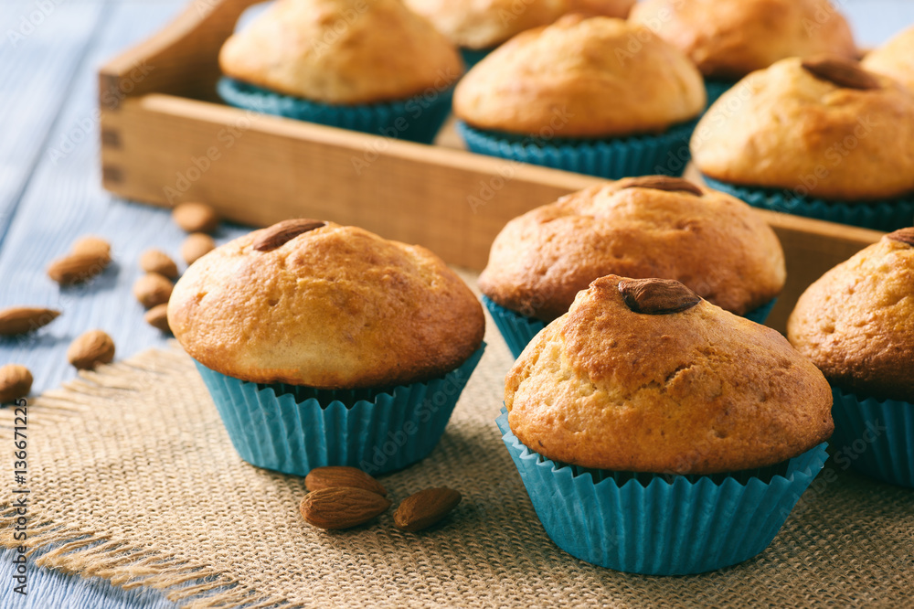 Sweet muffins with almond on blue wooden table.
