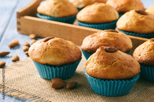 Sweet muffins with almond on blue wooden table.