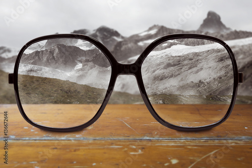 moderne Brille auf Tisch mit unscharfem Gebirge im Hintergrund