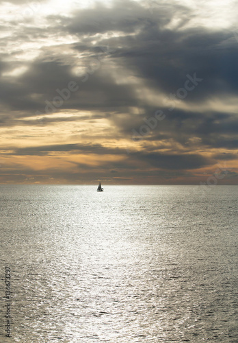 Dramatic evening seascape with sailing boat on dark sea