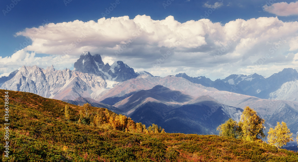 Magic autumn landscape and snow-capped mountain peaks. View of t