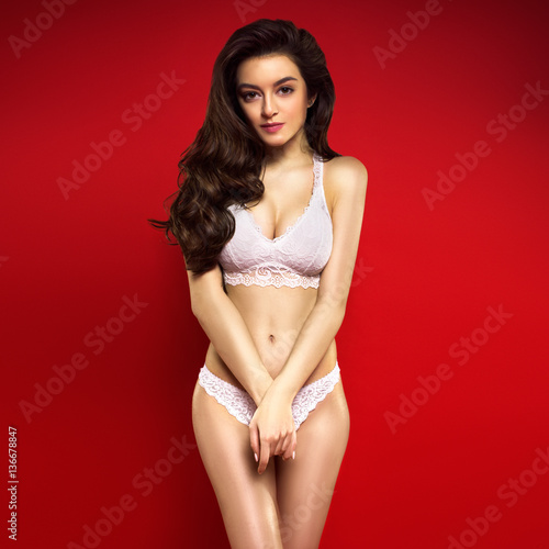 Beautiful Woman Posing In White Lingerie Isolated On Red Background