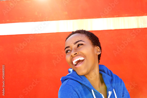attractive young black woman smiling against red wall