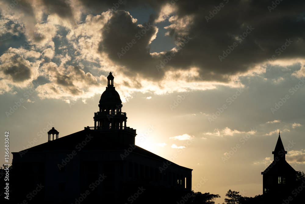 The silhouette old city hall building on twilight sky clouds with sunlight, Is one of the beautiful colonial style buildings. 