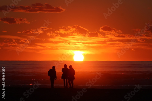 persone che ammirano il tramonto in spiaggia