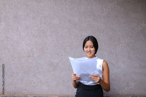 Pretty girl smiling, posing, holds paper in hands and looking aw photo