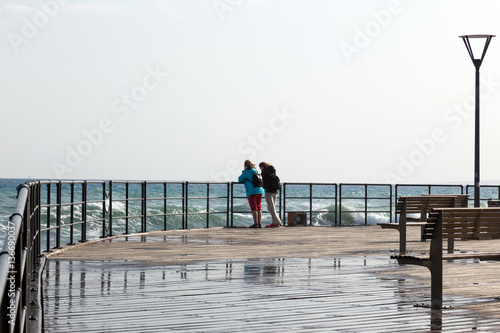 Two women on the pier during high waves